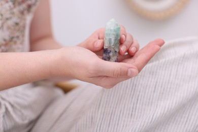 Photo of Woman with beautiful fluorite gemstone indoors, closeup