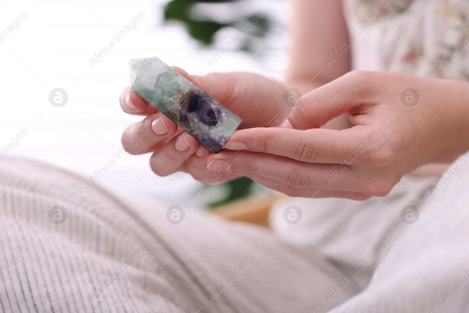 Photo of Woman with beautiful fluorite gemstone indoors, closeup