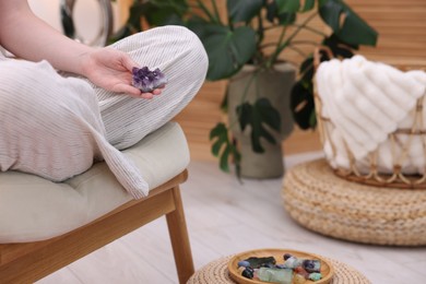 Photo of Woman with beautiful amethyst gemstone and other mineral stones indoors, closeup. Space for text