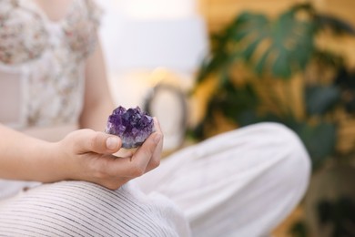 Photo of Woman with beautiful amethyst gemstone indoors, closeup. Space for text
