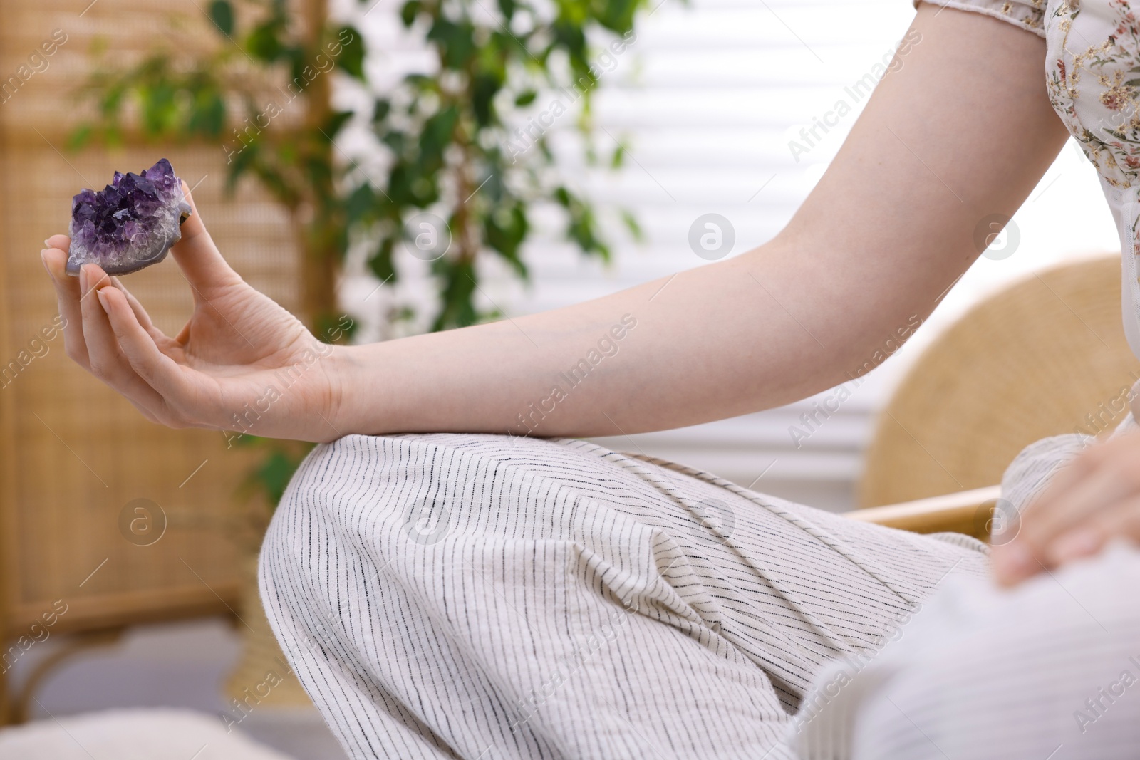 Photo of Woman with beautiful amethyst gemstone indoors, closeup
