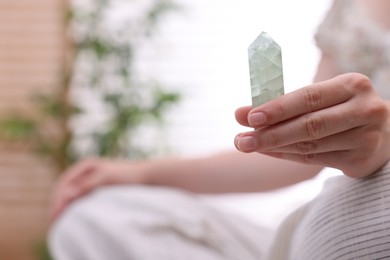 Photo of Woman with beautiful fluorite gemstone indoors, closeup. Space for text