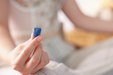 Photo of Woman with blue sodalite gemstone indoors, closeup