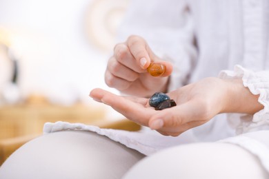 Photo of Woman with different beautiful gemstones indoors, closeup