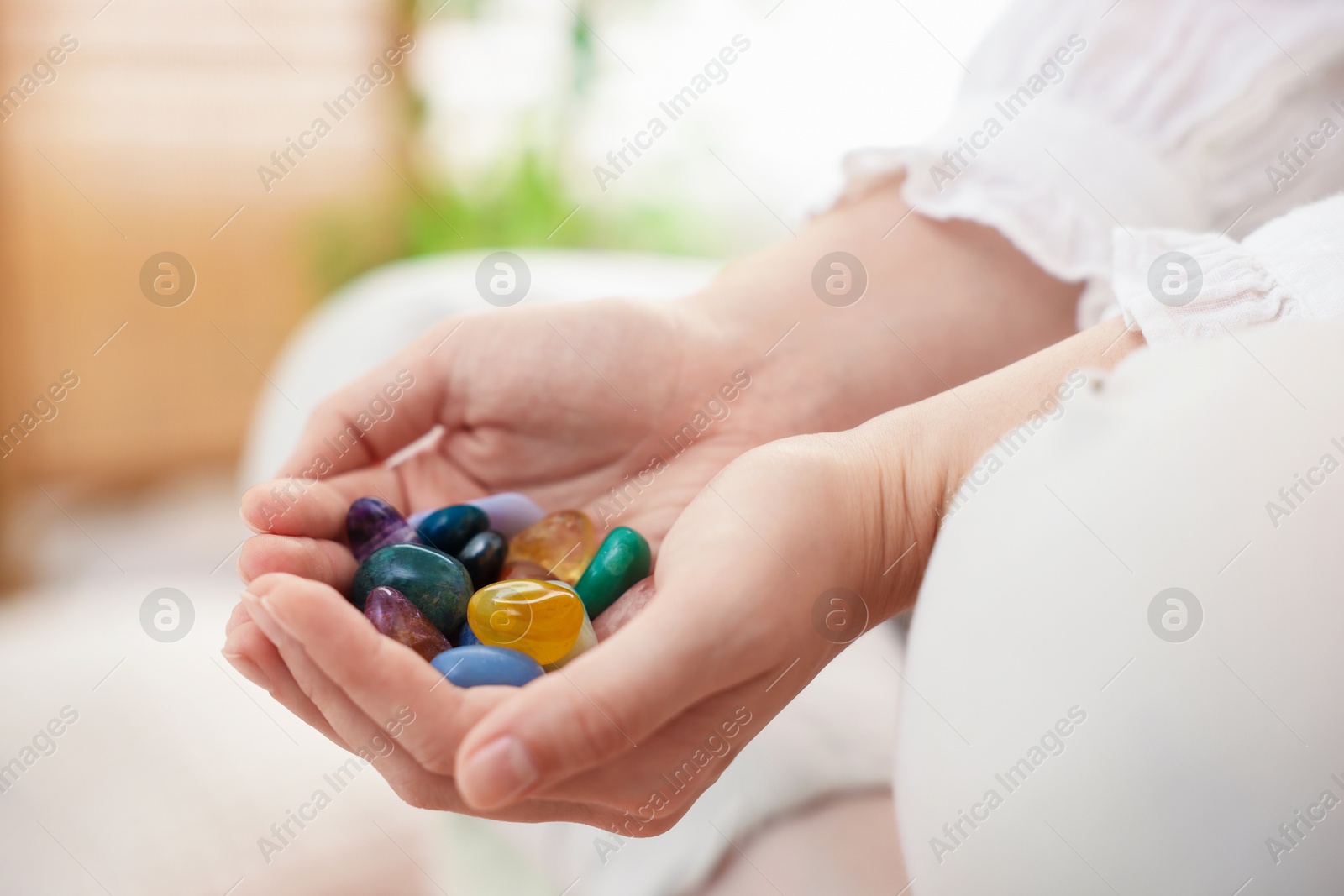 Photo of Woman with different beautiful gemstones indoors, closeup