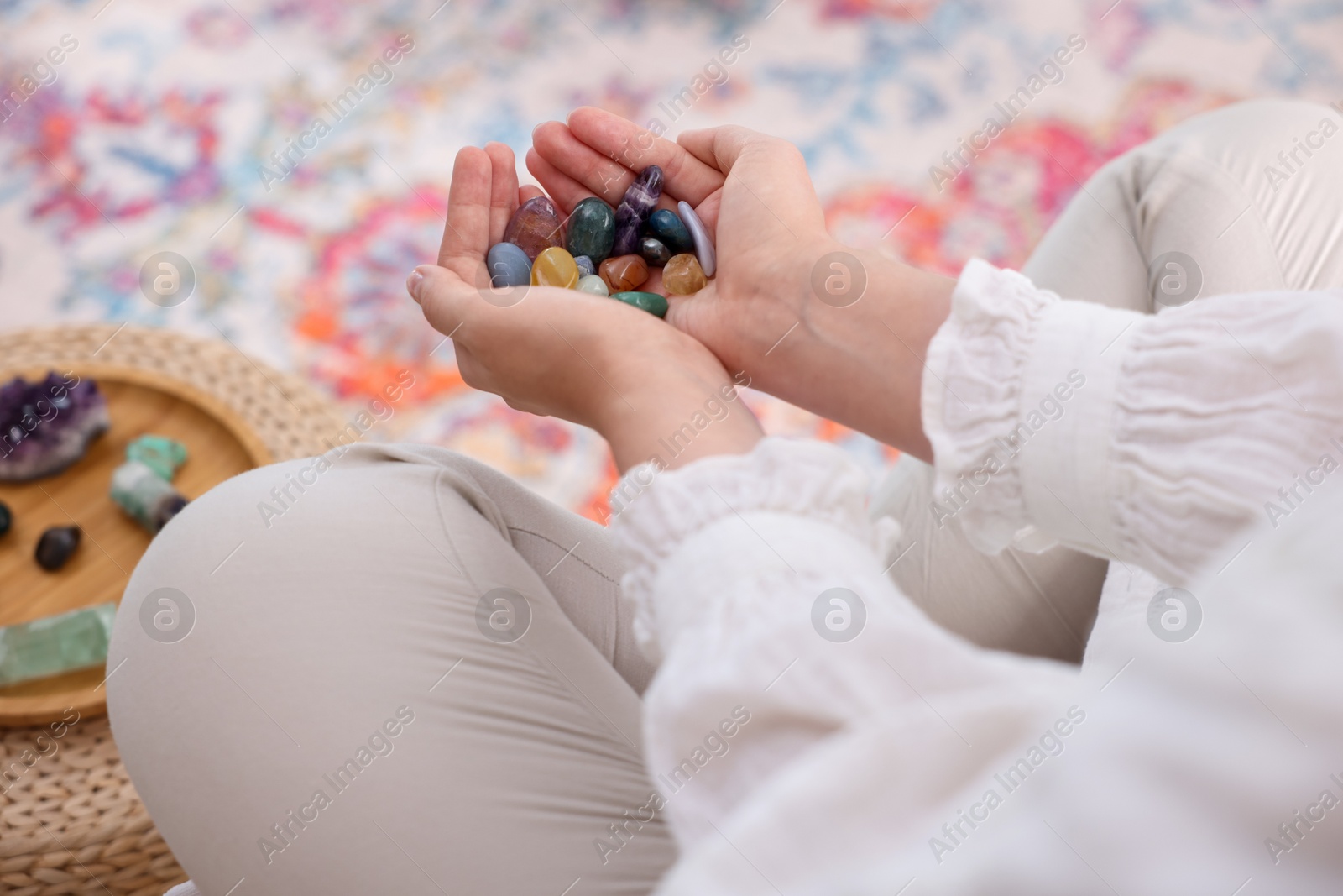 Photo of Woman with different beautiful gemstones indoors, closeup