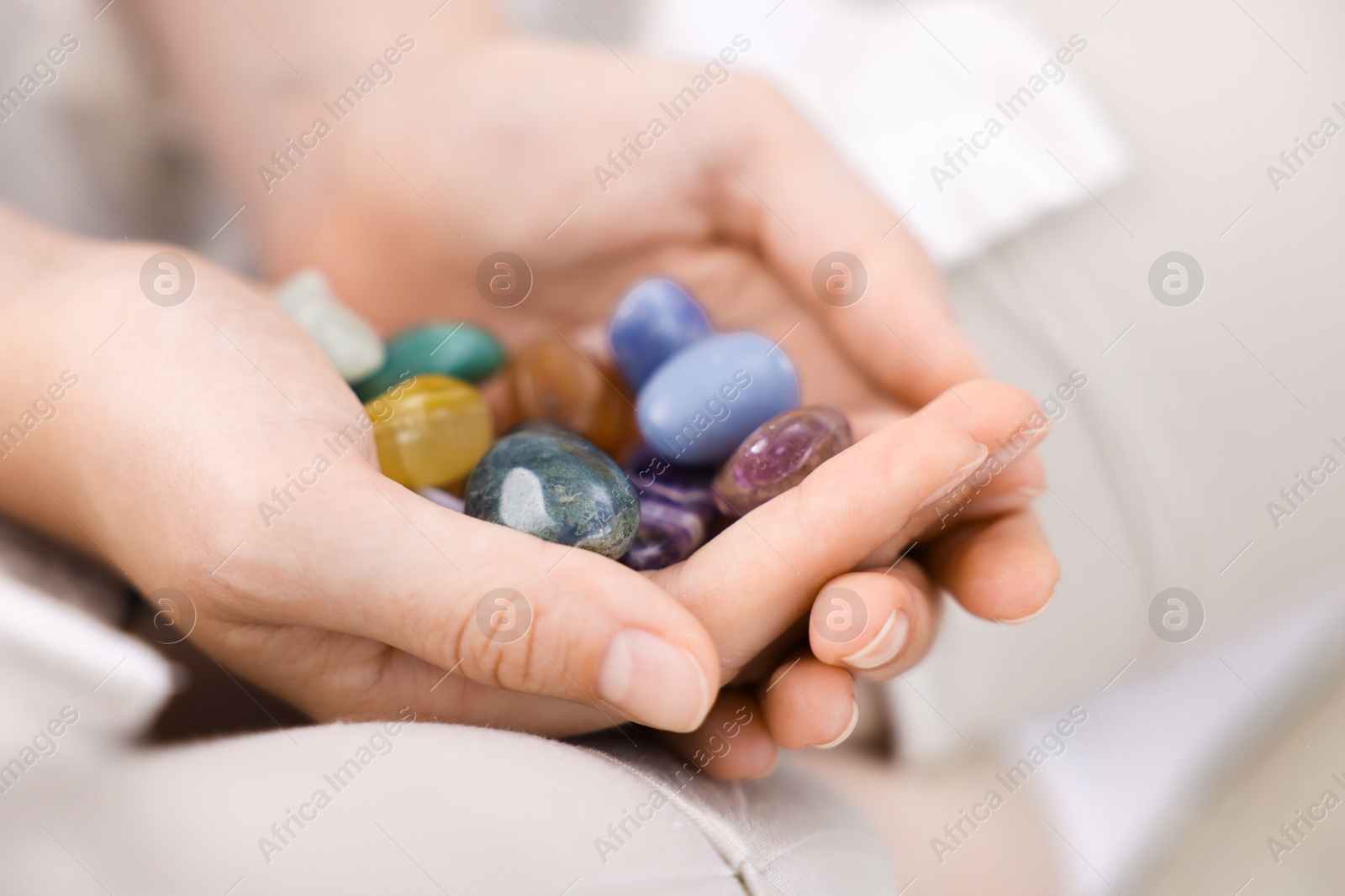 Photo of Woman with different beautiful gemstones indoors, closeup