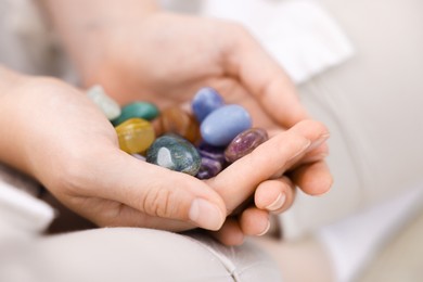 Photo of Woman with different beautiful gemstones indoors, closeup