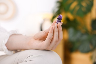 Photo of Woman with beautiful amethyst gemstone indoors, closeup. Space for text