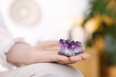 Photo of Woman with beautiful amethyst gemstone indoors, closeup