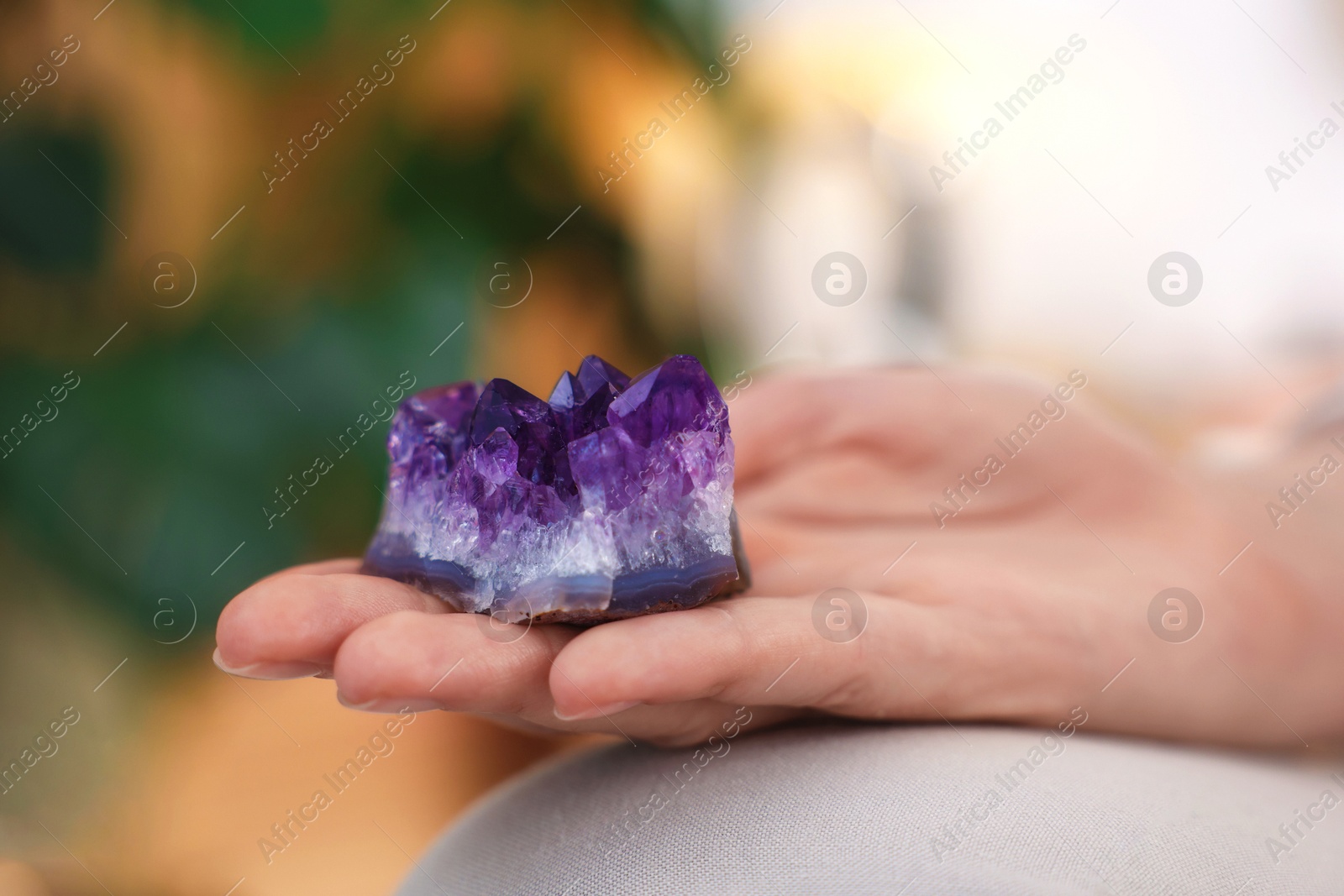 Photo of Woman with beautiful amethyst gemstone indoors, closeup