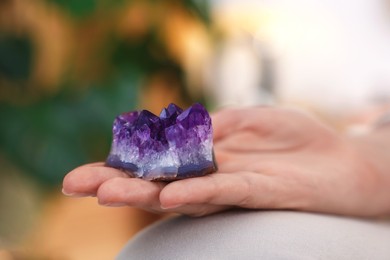 Photo of Woman with beautiful amethyst gemstone indoors, closeup