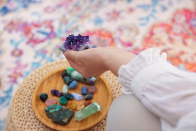 Photo of Woman with beautiful amethyst gemstone and other mineral stones indoors, closeup