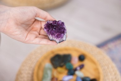 Photo of Woman with beautiful amethyst gemstone and other mineral stones indoors, closeup. Space for text