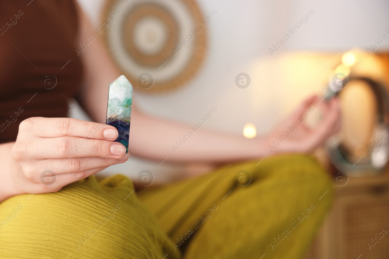 Photo of Woman with beautiful fluorite gemstone meditating indoors, closeup