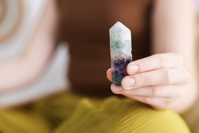 Photo of Woman with beautiful fluorite gemstone indoors, closeup. Space for text