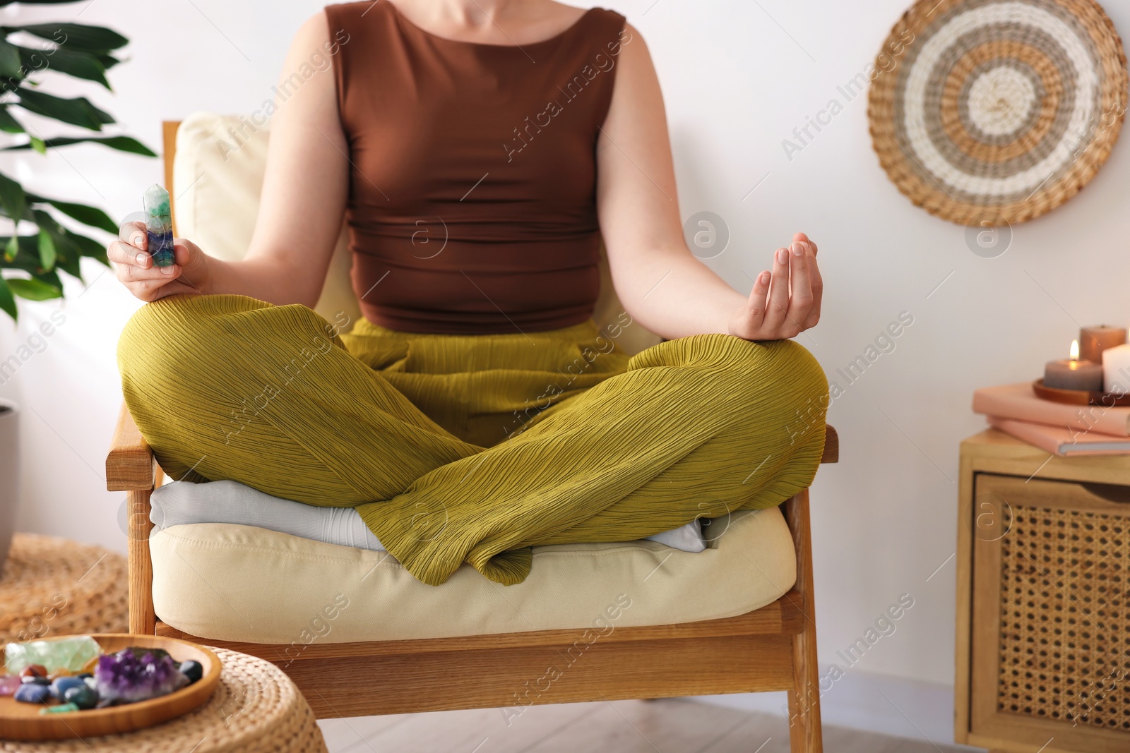 Photo of Woman with beautiful fluorite gemstone meditating indoors, closeup