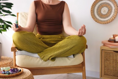 Photo of Woman with beautiful fluorite gemstone meditating indoors, closeup