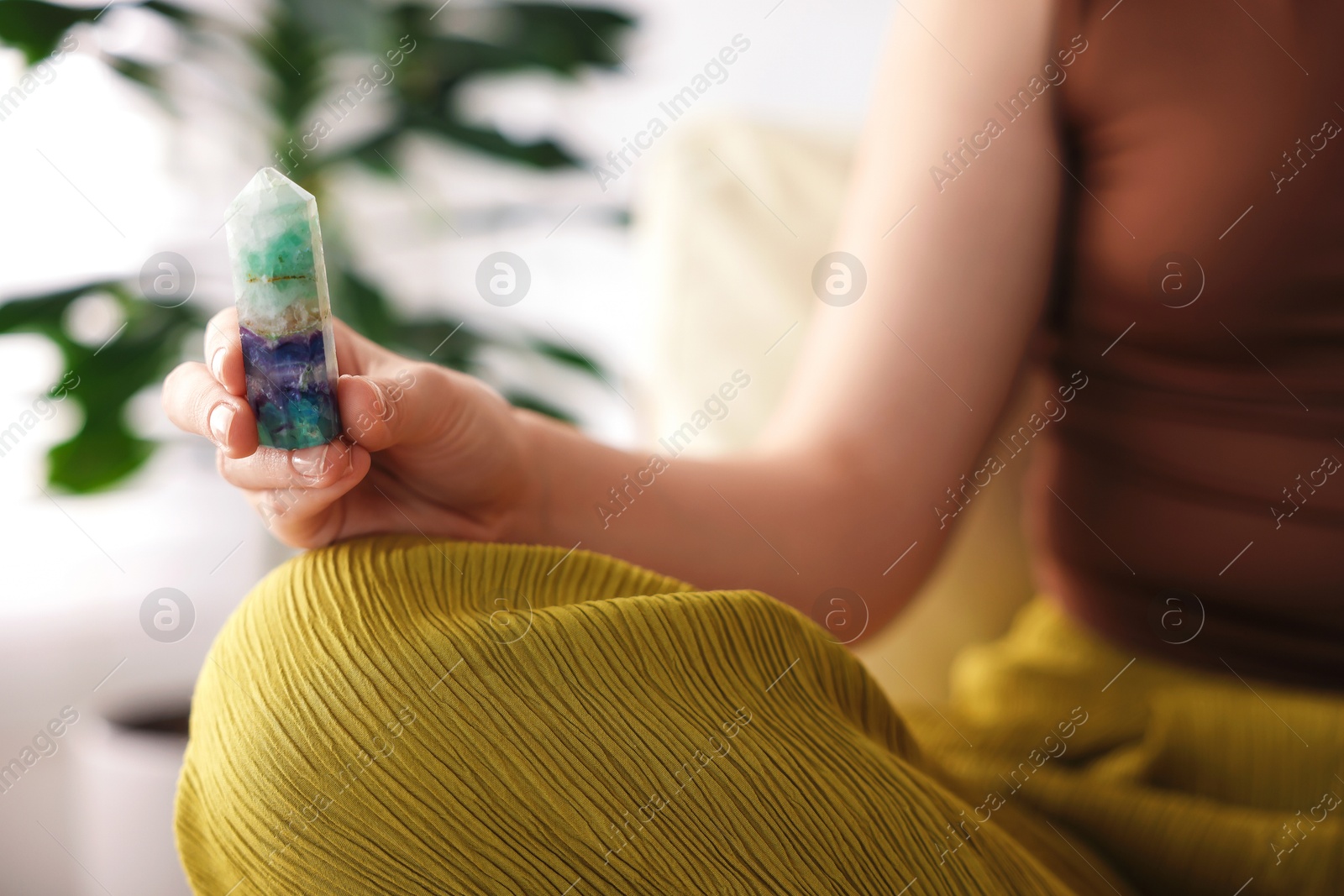 Photo of Woman with beautiful fluorite gemstone indoors, closeup