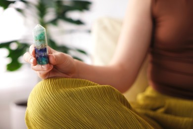 Photo of Woman with beautiful fluorite gemstone indoors, closeup