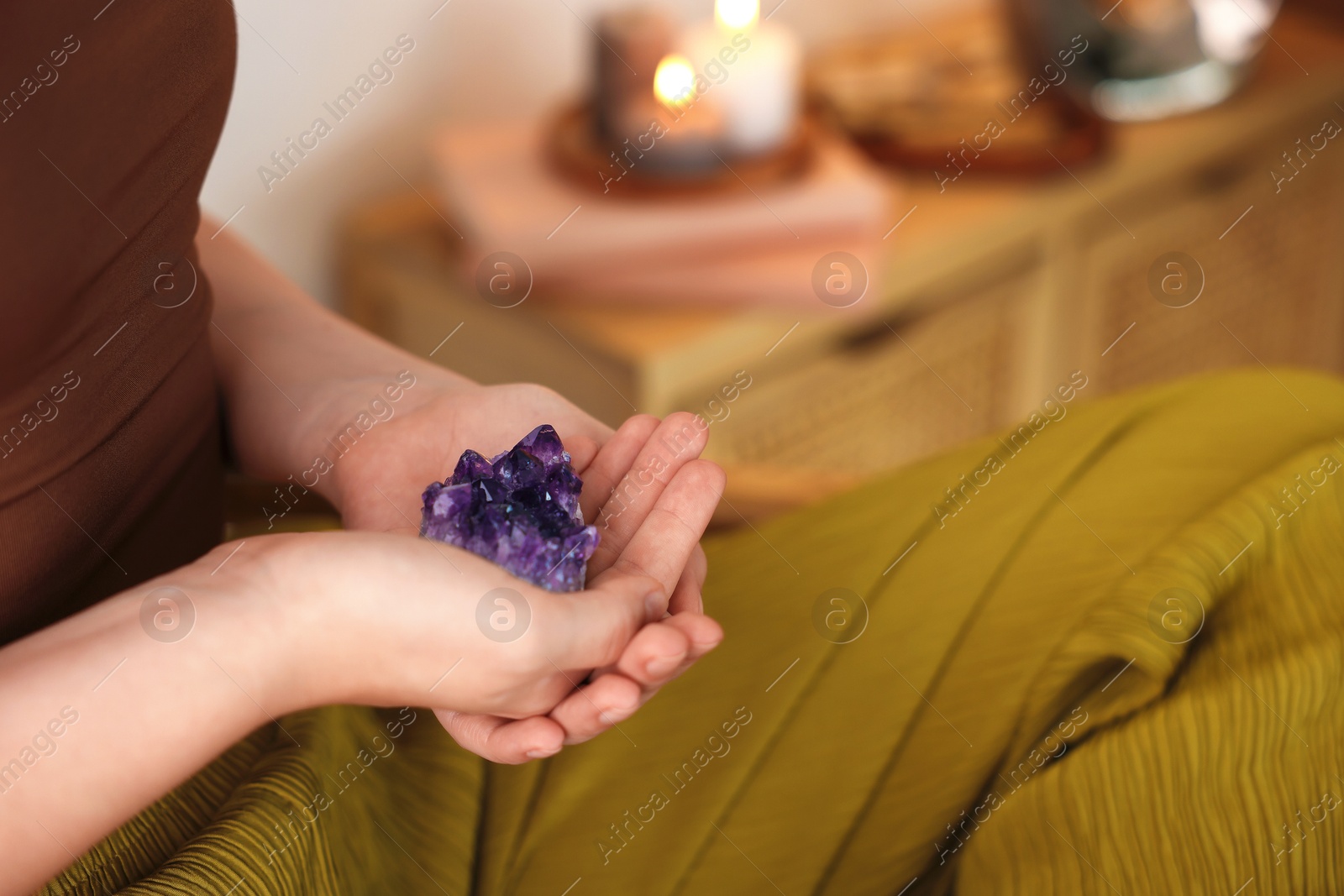 Photo of Woman with beautiful amethyst gemstone indoors, closeup