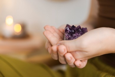 Photo of Woman with beautiful amethyst gemstone indoors, closeup. Space for text