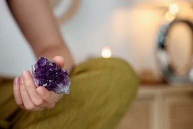 Photo of Woman with beautiful amethyst gemstone indoors, closeup. Space for text