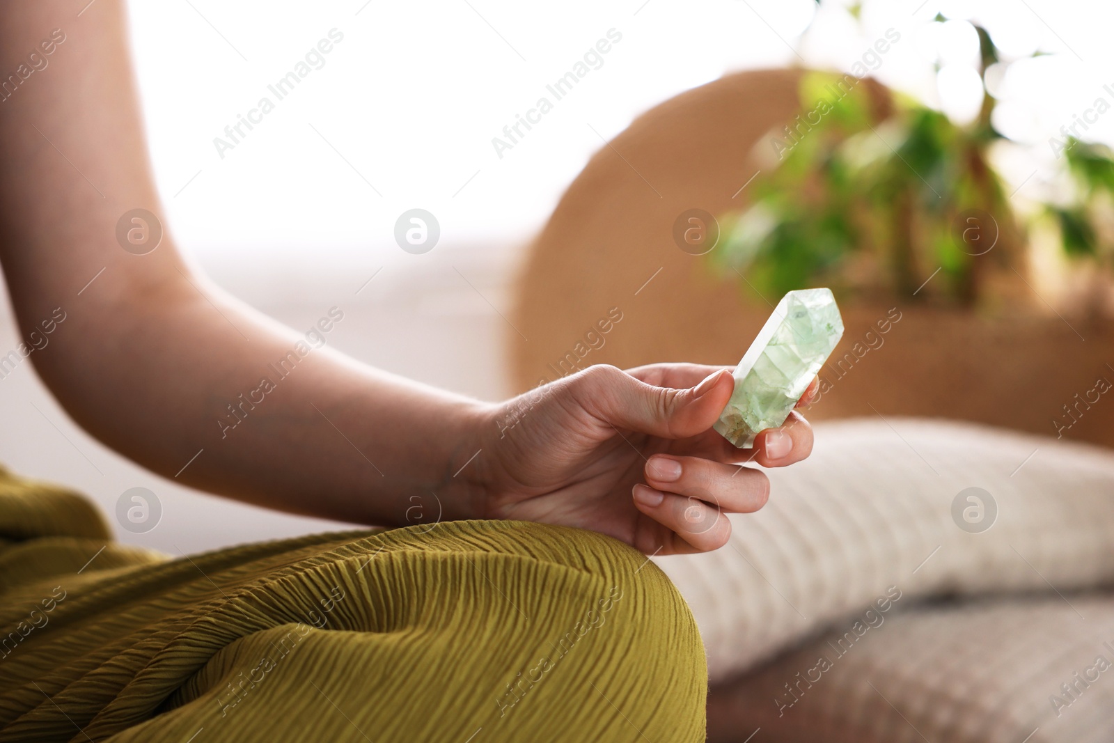 Photo of Woman with beautiful fluorite gemstone indoors, closeup