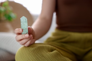 Photo of Woman with beautiful fluorite gemstone indoors, closeup