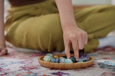 Photo of Woman with different beautiful gemstones indoors, closeup