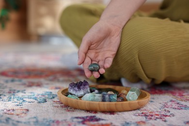Photo of Woman with different beautiful gemstones indoors, closeup. Space for text
