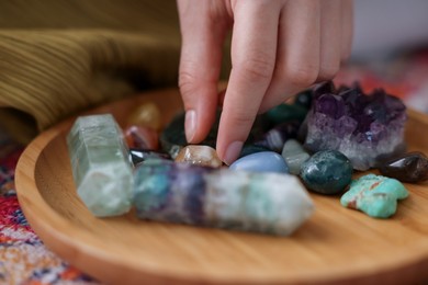 Photo of Woman with different beautiful gemstones indoors, closeup