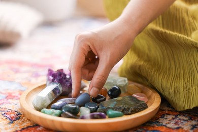 Photo of Woman with different beautiful gemstones indoors, closeup