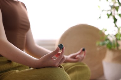 Photo of Woman with beautiful gemstones meditating indoors, closeup. Space for text