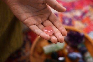 Photo of Woman with beautiful rose quartz indoors, closeup. Natural gemstone