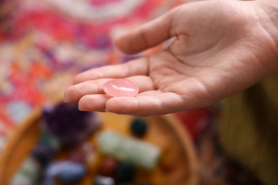 Photo of Woman with beautiful rose quartz indoors, closeup. Natural gemstone