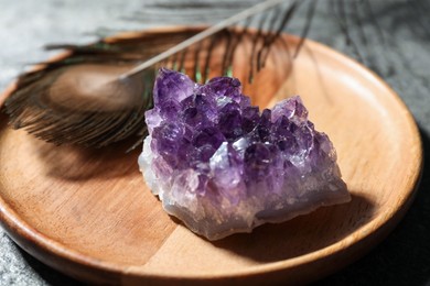 Photo of Beautiful amethyst gemstone and peacock feather on table, closeup