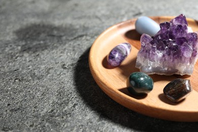 Photo of Different beautiful gemstones on grey table, closeup. Space for text