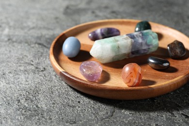 Photo of Different beautiful gemstones on grey table, closeup. Space for text