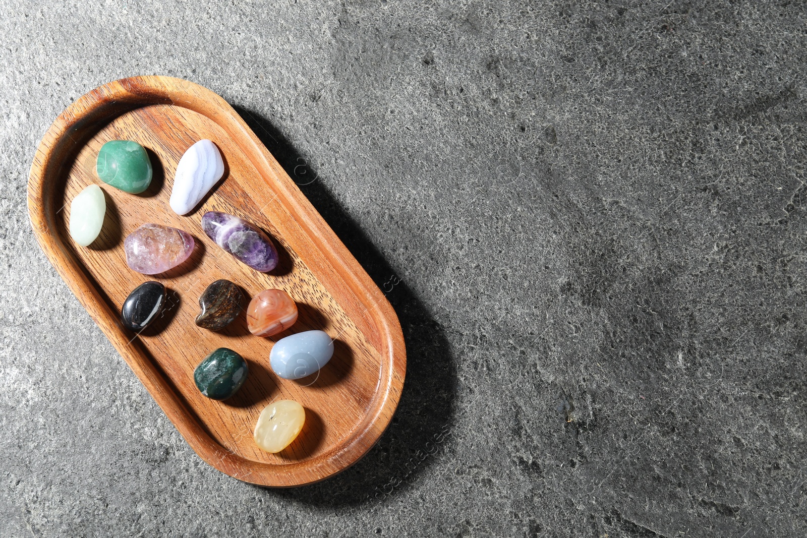 Photo of Different beautiful gemstones on grey table, top view. Space for text