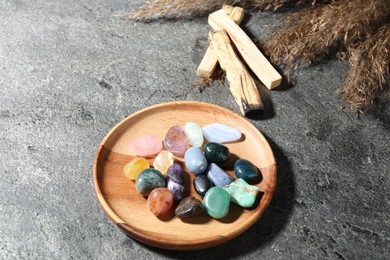Photo of Different beautiful gemstones, palo santo and dried reeds on grey table, closeup