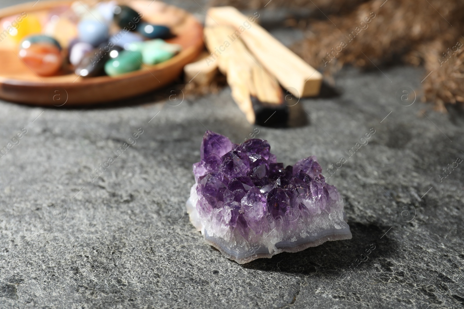 Photo of Different beautiful gemstones, palo santo and dried reeds on grey table, closeup