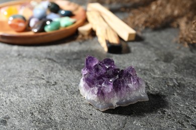 Photo of Different beautiful gemstones, palo santo and dried reeds on grey table, closeup