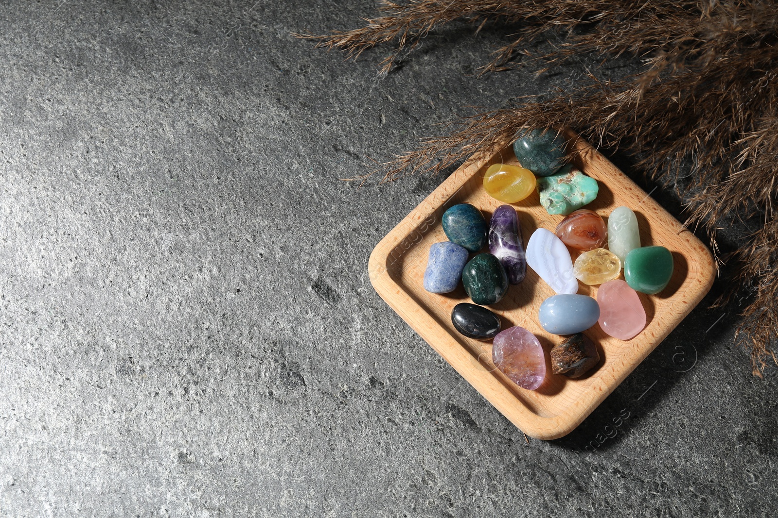 Photo of Different beautiful gemstones and dried reeds on grey table, flat lay. Space for text