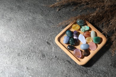 Photo of Different beautiful gemstones and dried reeds on grey table, flat lay. Space for text