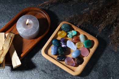 Photo of Different beautiful gemstones, palo santo, burning candle and dried reeds on grey table, flat lay