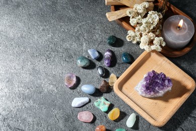 Photo of Different beautiful gemstones, palo santo, candle and dried flowers on grey table, flat lay. Space for text
