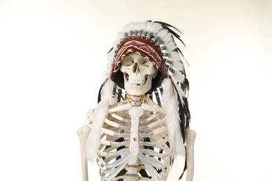Photo of Artificial human skeleton wearing warbonnet (Native American chief headdress) isolated on white