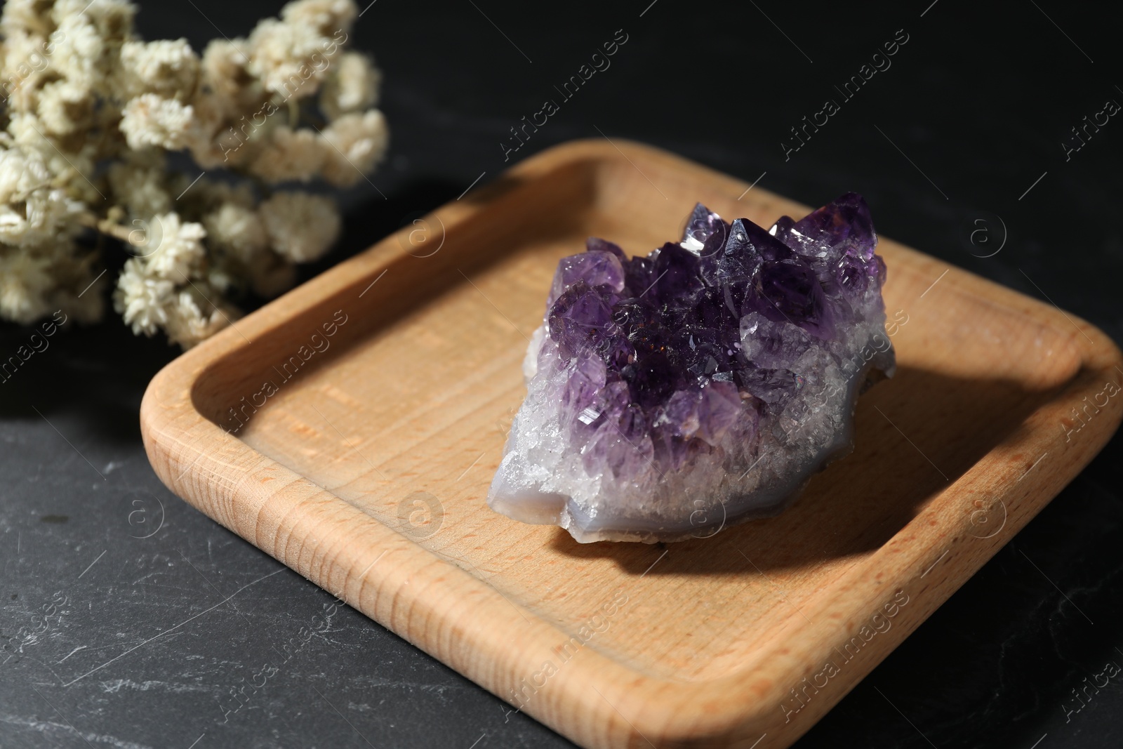 Photo of Beautiful amethyst gemstone and dried flowers on black table, closeup