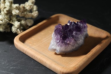 Photo of Beautiful amethyst gemstone and dried flowers on black table, closeup
